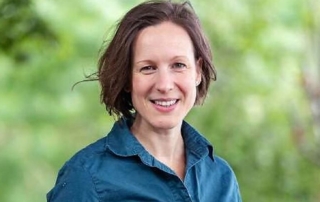 Dr Michelle Freeman, President of Forestry Australia, smiling in a teal field shirt outdoors against green foliage
