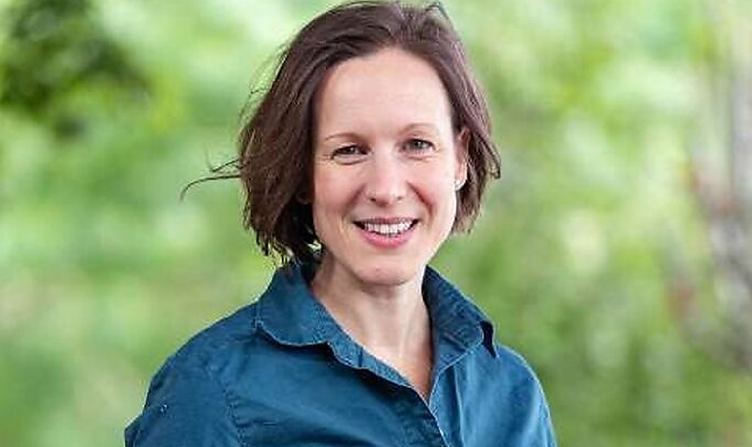 Dr Michelle Freeman, President of Forestry Australia, smiling in a teal field shirt outdoors against green foliage